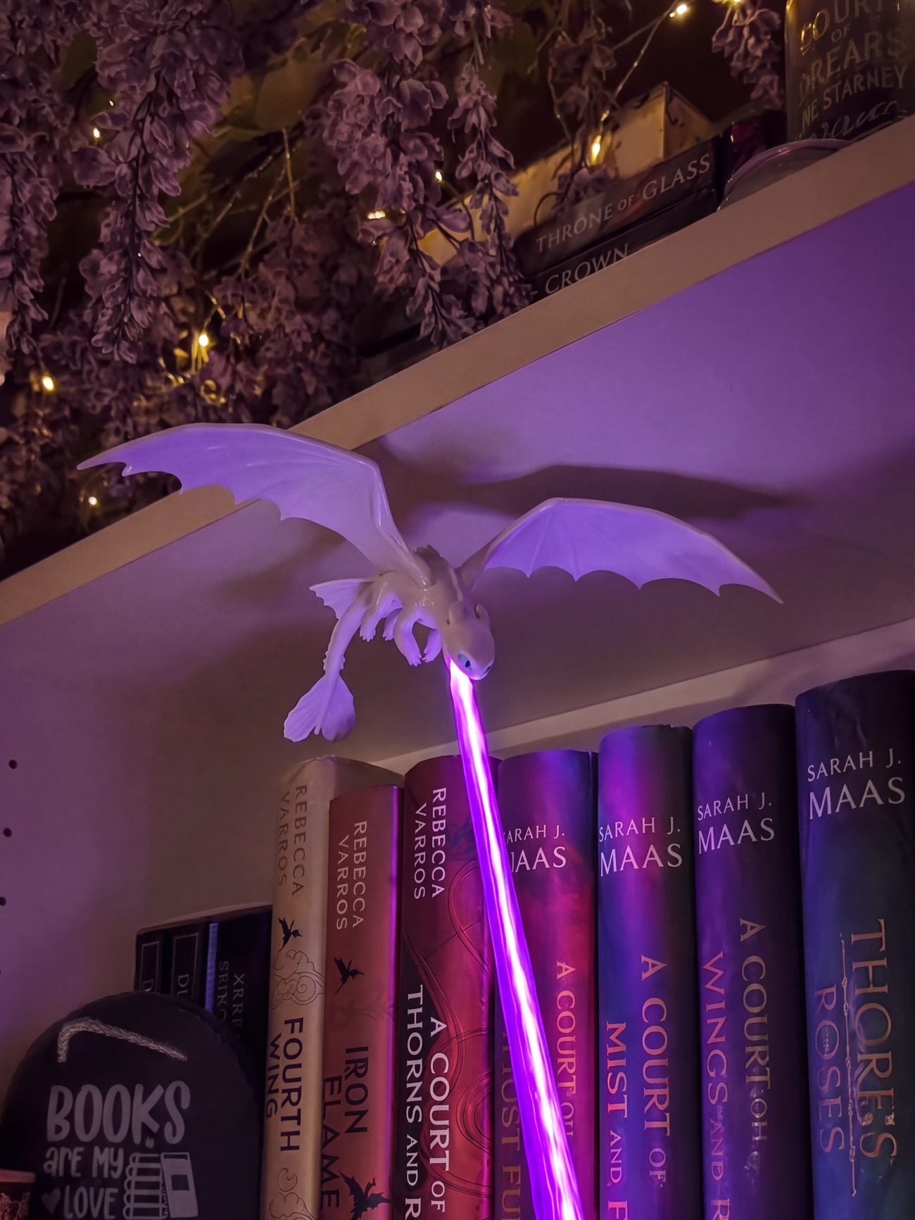 A Light Fury lit violet over a shelf of books