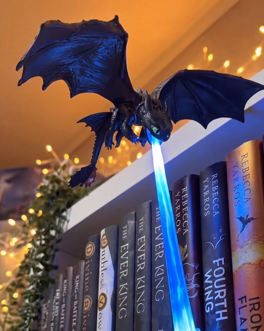 Toothless lit blue on a shelf strung with fairy lights